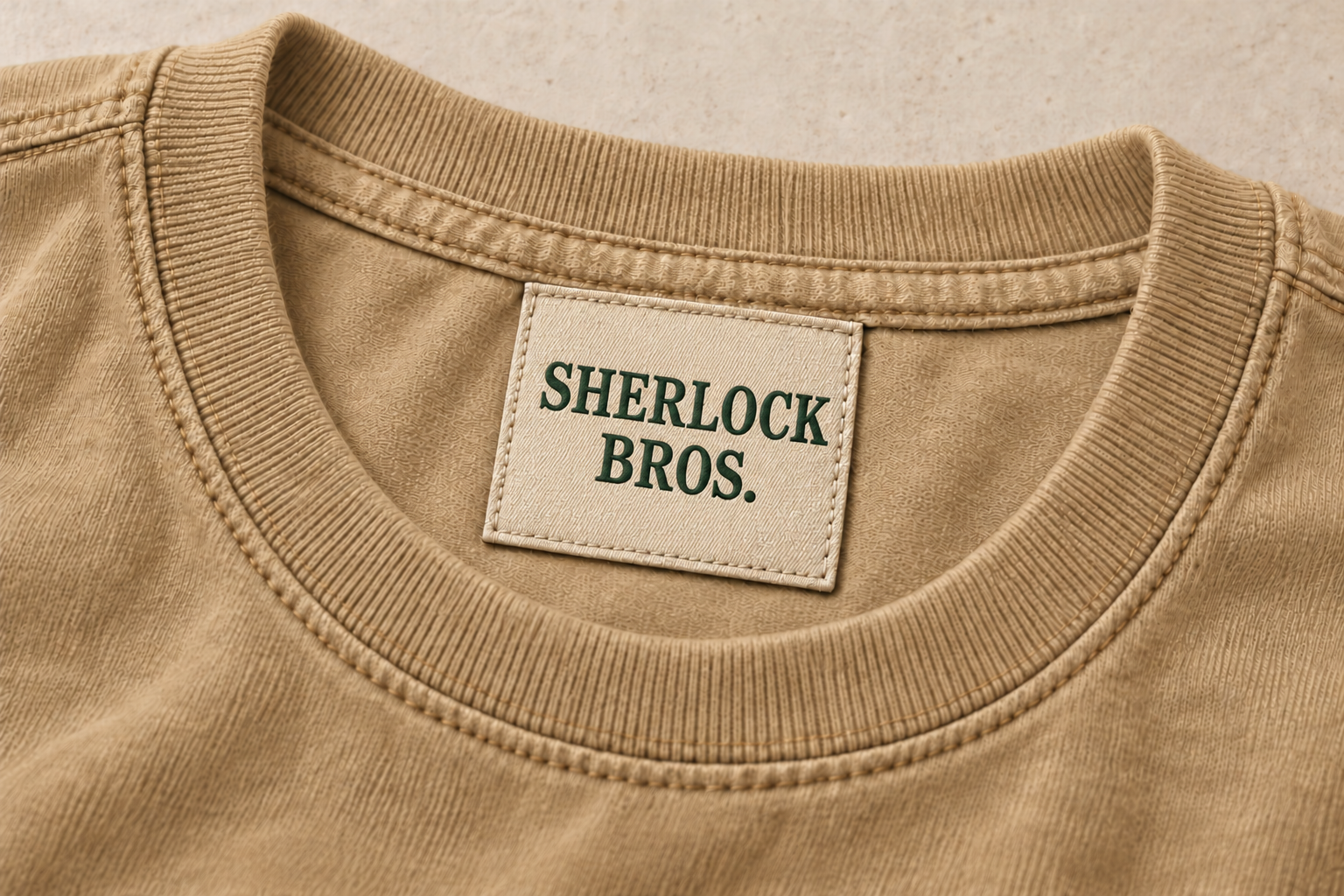 Design concept close-up of a sand tee’s ribbed neckline and sewn-in Sherlock Bros. woven neck label